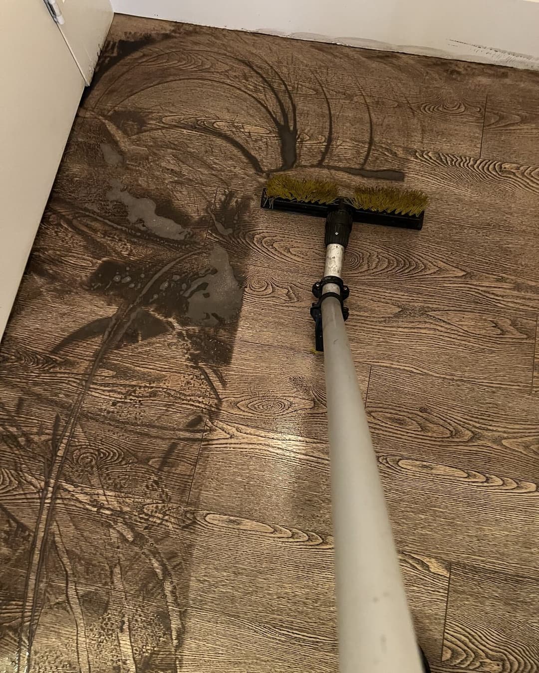 Dirty slurry lifting off a vinyl plank floor during scrubbing
